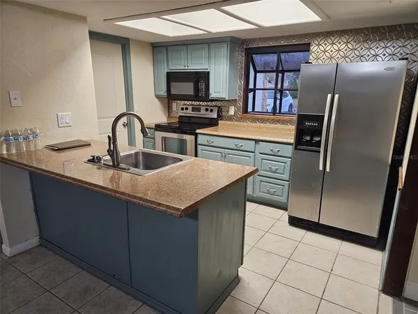 a kitchen with stainless steel appliances granite countertop a refrigerator a sink a stove counter space and cabinetry