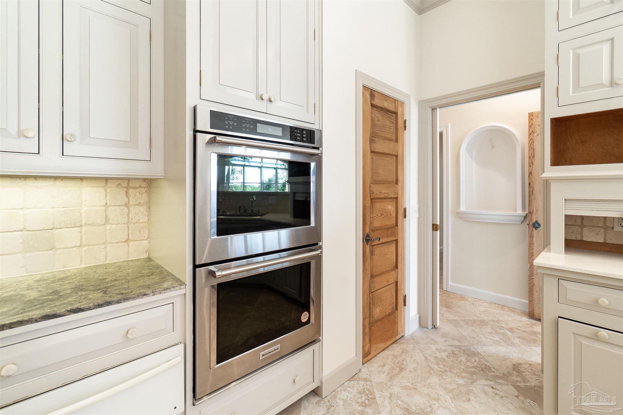 1725 E Lane Pensacola, FL 32501 - Photo 22 of 72 a kitchen with granite countertop white cabinets and stainless steel appliances
