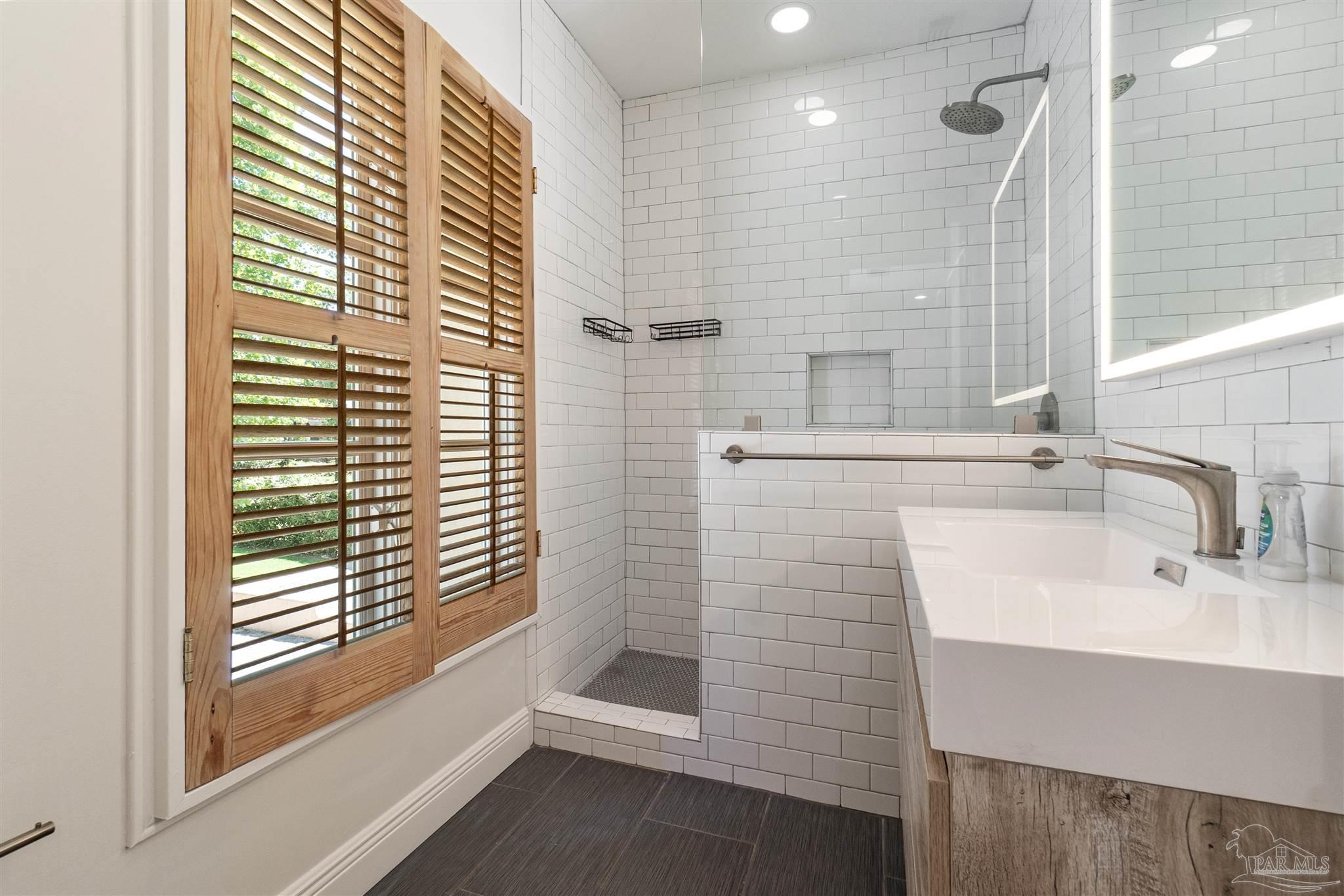 1725 E Lane Pensacola, FL 32501 - Photo 47 of 72 a bathroom with a sink a shower and a mirror
