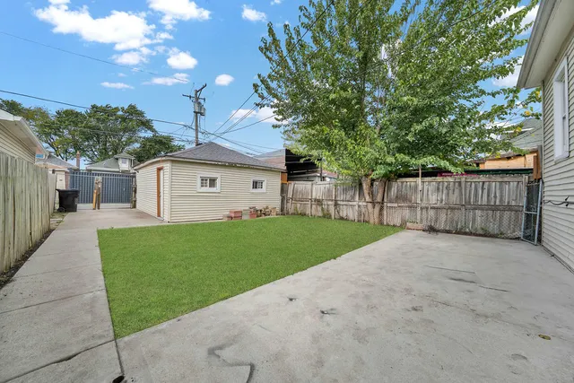 a view of a backyard with large trees and wooden fence