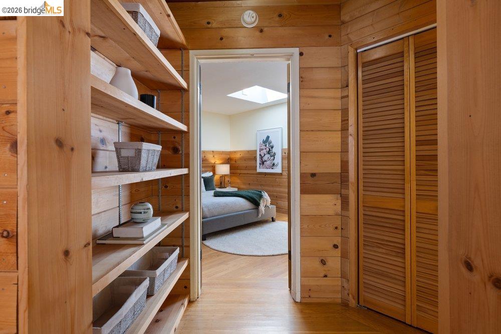287 Purdue Avenue Kensington, CA 94708 - Photo 39 of 60 Wood-paneled hallway featuring built-in shelving, louvered closet doors, and hardwood flooring