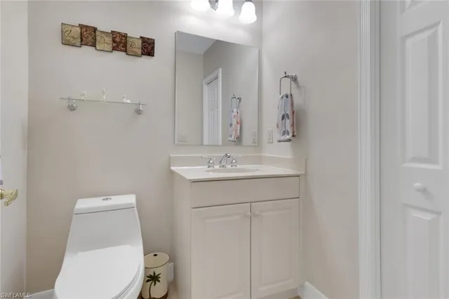 a bathroom with a toilet a sink a mirror and vanity