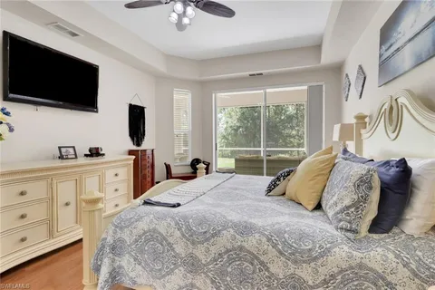 a spacious bedroom with a bed a flat screen tv and a window
