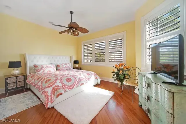 a bedroom with a bed television window and wooden floor