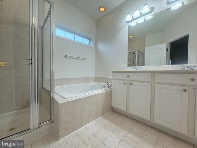 a spacious bathroom with a tub a double vanity sink and mirror