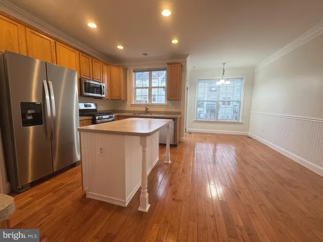 a kitchen with stainless steel appliances granite countertop a refrigerator a sink dishwasher a stove with wooden floors and cabinets