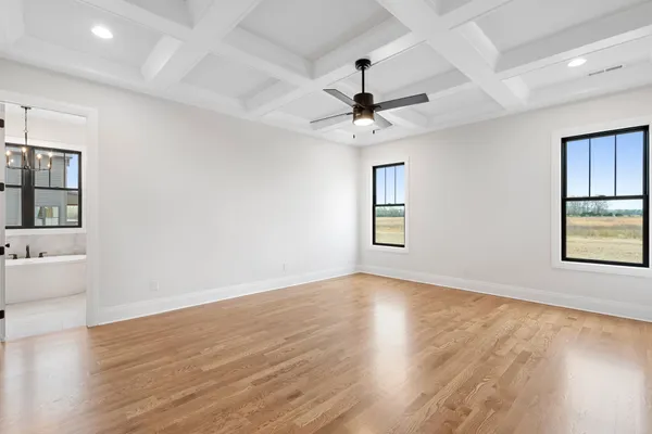 a view of an empty room with window and wooden floor