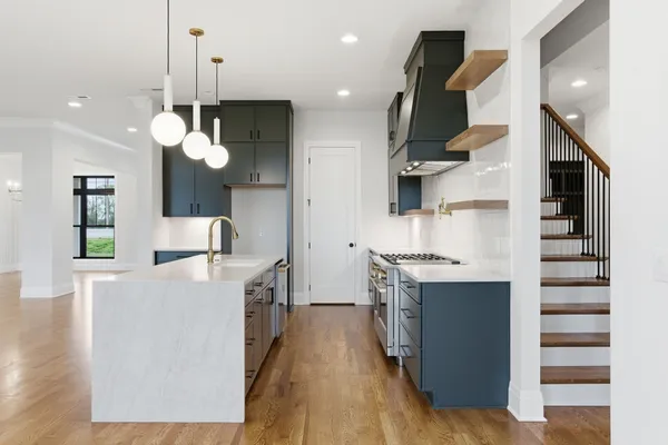 a kitchen with stainless steel appliances granite countertop a sink a stove and a wooden floors