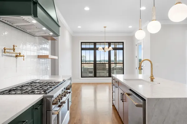 a kitchen with kitchen island a sink appliances cabinets and a large window