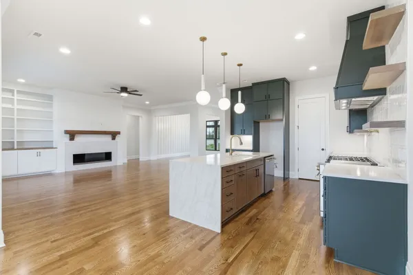 a large kitchen with kitchen island a stove a sink a center island and wooden floor