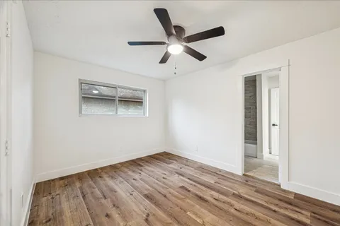 a view of empty room with wooden floor and ceiling fan