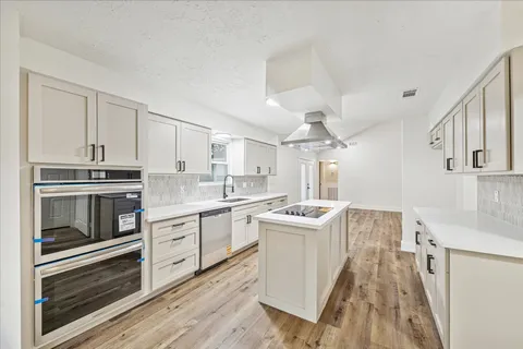 a kitchen with stainless steel appliances granite countertop a stove and white cabinets