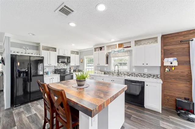 a kitchen with stainless steel appliances granite countertop a stove top oven a sink dishwasher and white cabinets with wooden floor