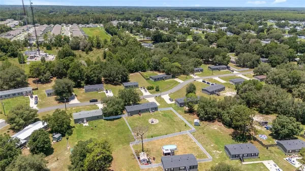 an aerial view of residential houses with outdoor space and trees