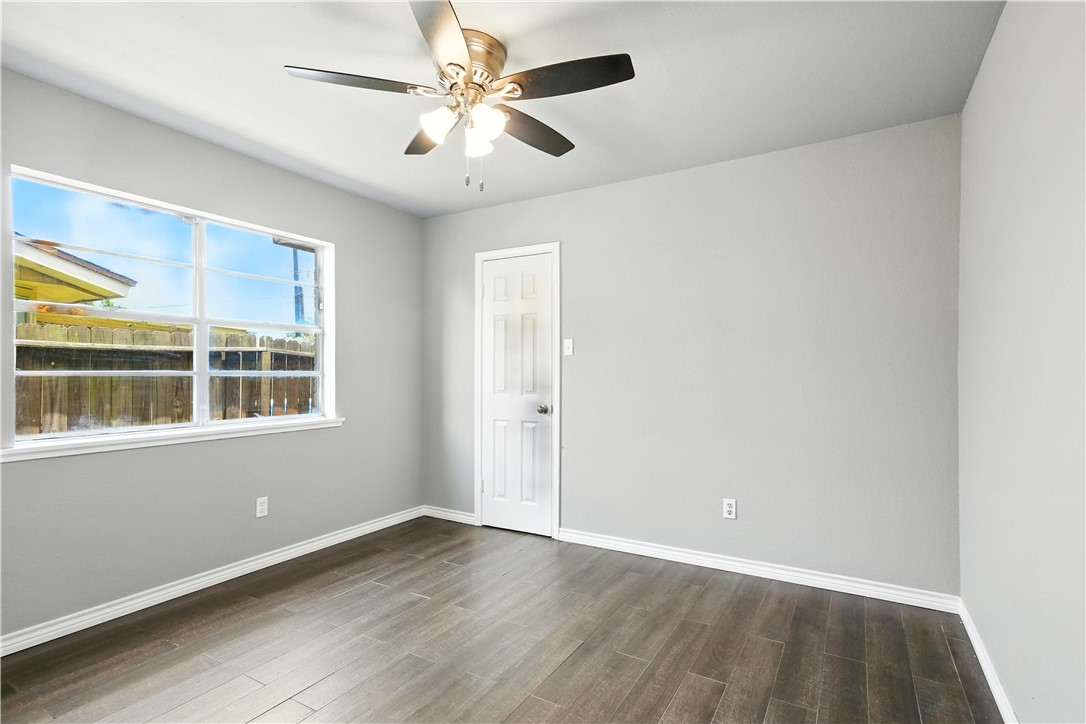 833 Orleans Drive Corpus Christi, TX 78418 - Photo 12 of 18 an empty room with wooden floor chandelier fan and windows