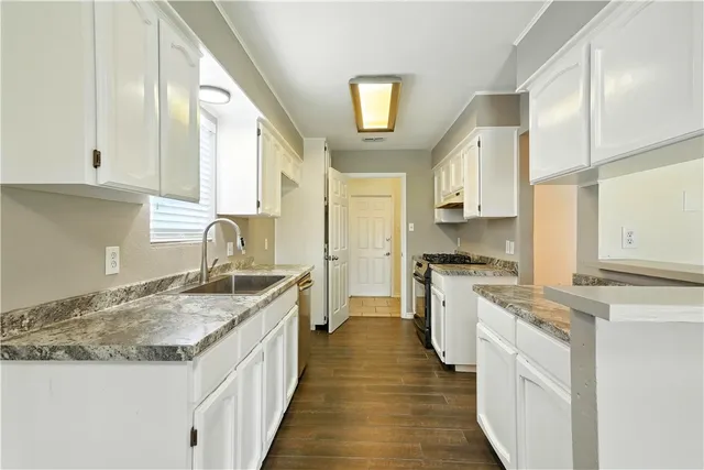 a kitchen with granite countertop kitchen island a stove a sink a counter space and cabinets