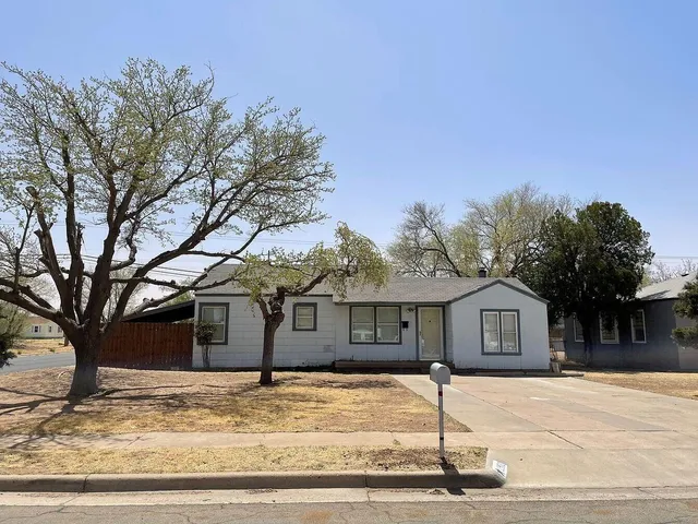 a front view of a house with a garden and trees