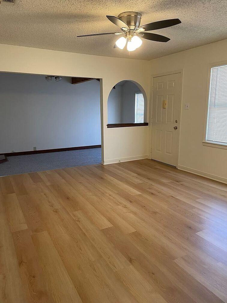1301 41st Street Lubbock, TX 79412 - Photo 3 of 8 an empty room with wooden floor chandelier fan and windows