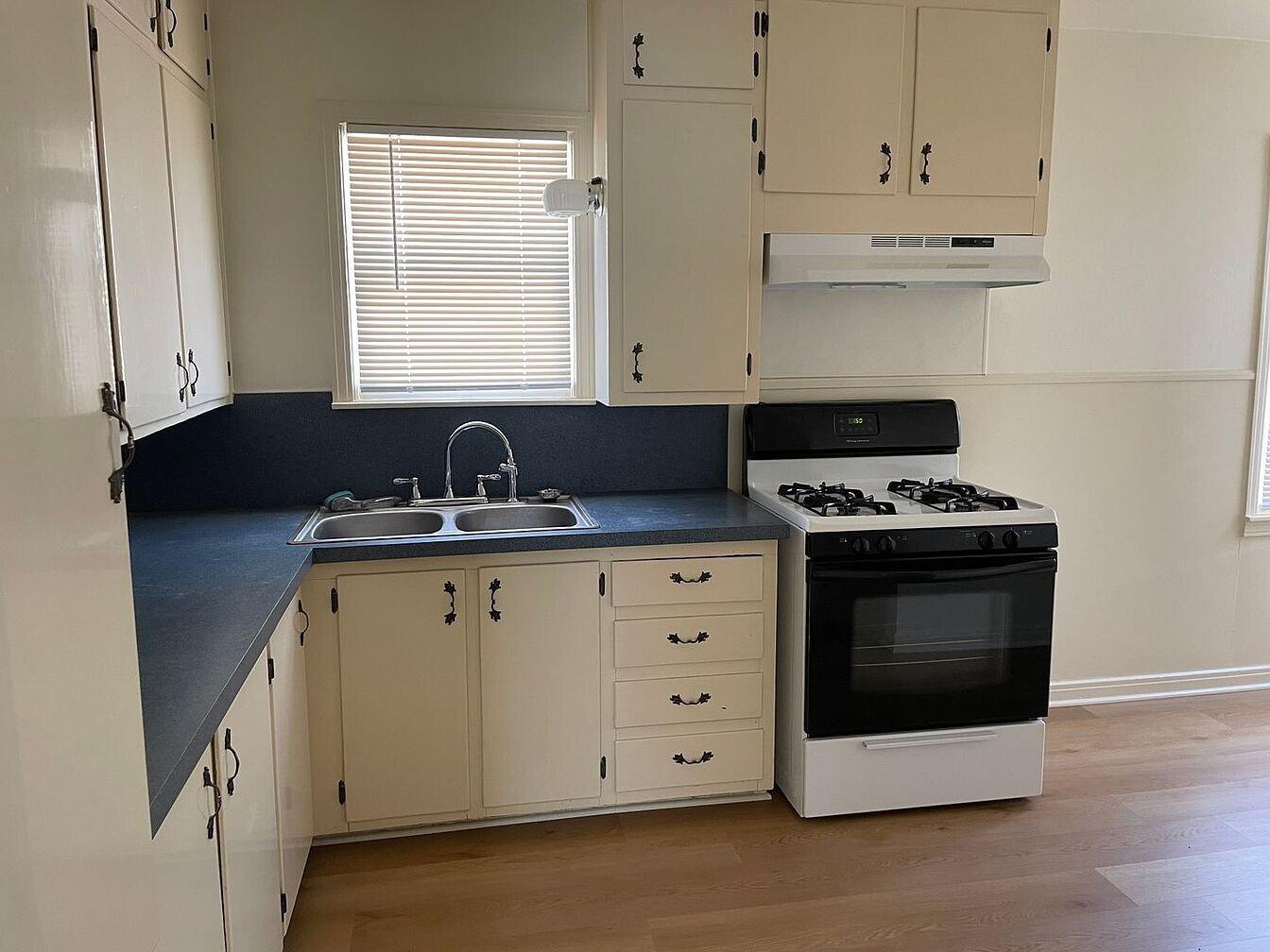 1301 41st Street Lubbock, TX 79412 - Photo 5 of 8 a kitchen with granite countertop white cabinets and black appliances