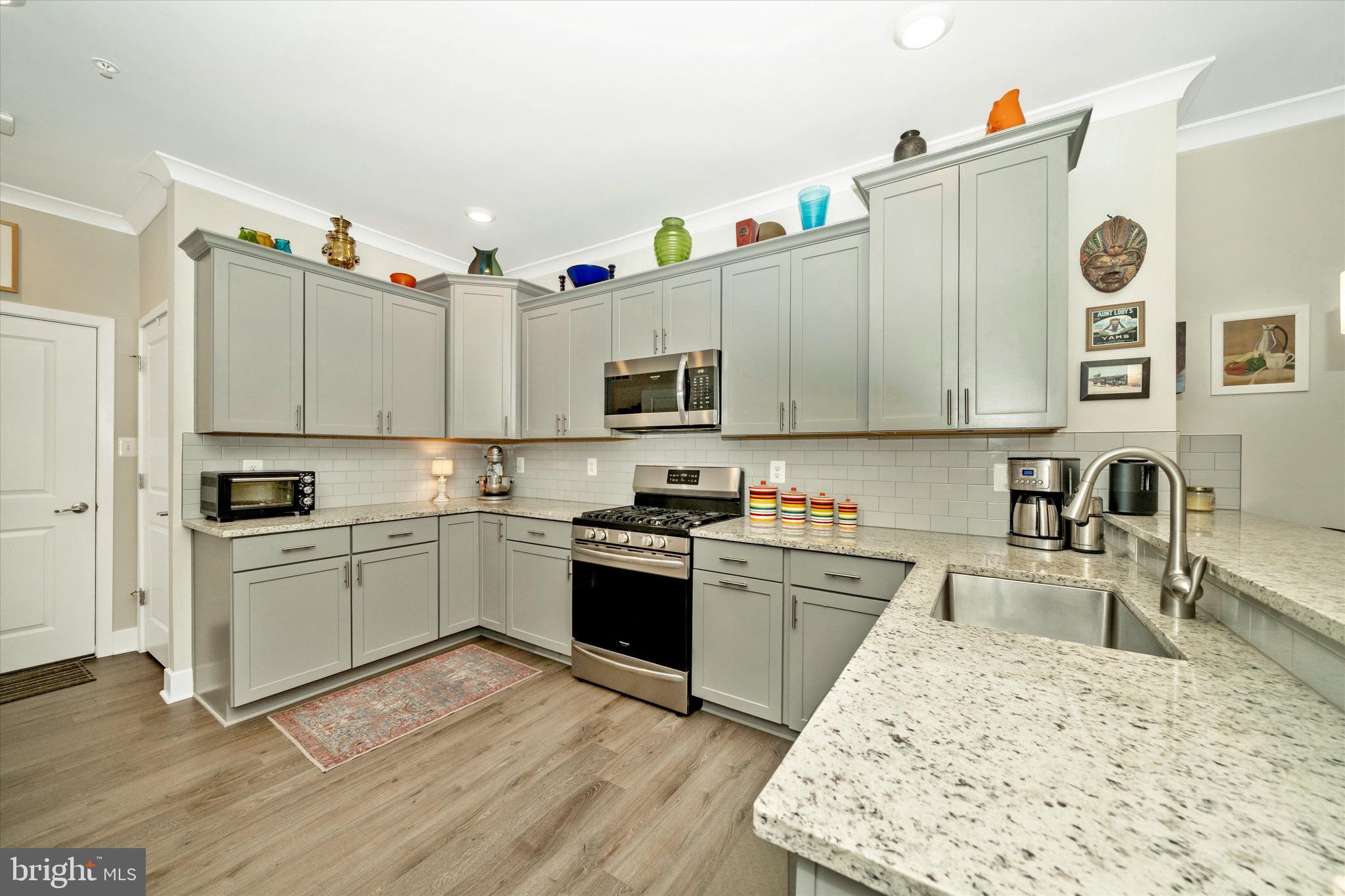7920 Potter Place, Unit 920B Elkridge, MD 21075 - Photo 17 of 57 a kitchen with granite countertop a sink stove and white cabinets