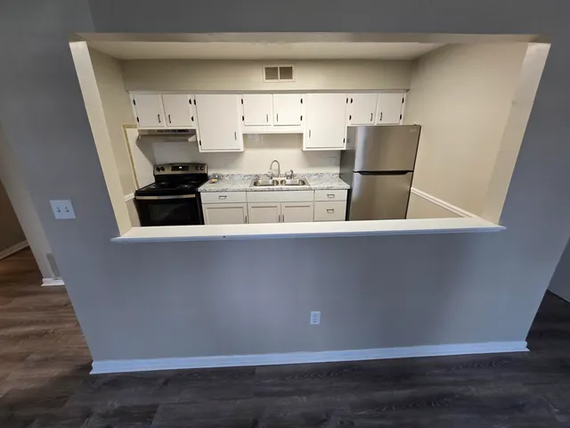 a kitchen with stainless steel appliances a refrigerator a stove a sink and white cabinets