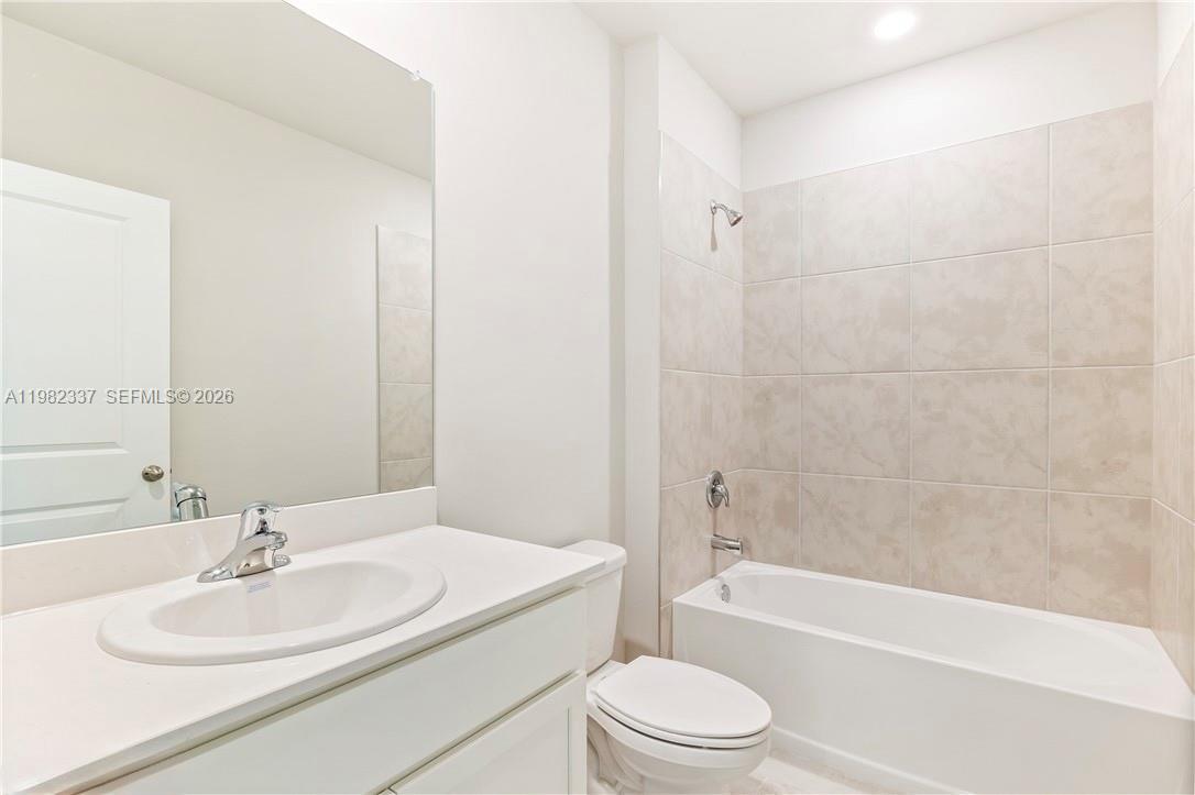 5215 Butte Street Lehigh Acres, FL 33971 - Photo 11 of 15 a bathroom with a toilet a sink and a bathtub