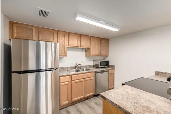 a kitchen with stainless steel appliances granite countertop a refrigerator a sink dishwasher a stove with wooden cabinets