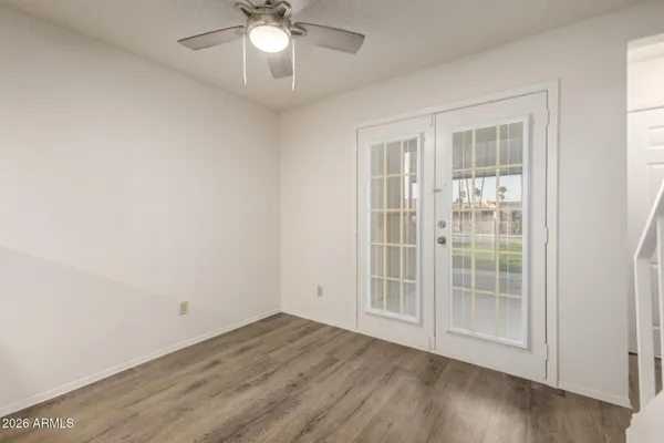an empty room with wooden floor fan and windows