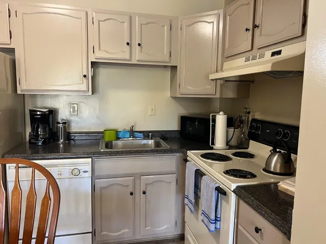 a kitchen with stainless steel appliances granite countertop a stove a sink and a white cabinets