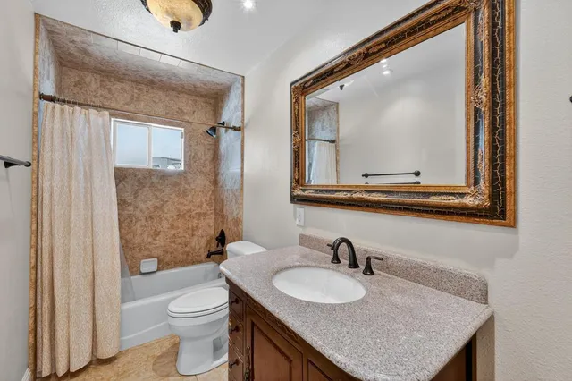 a bathroom with a granite countertop sink vanity mirror and toilet