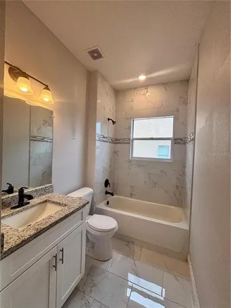 a bathroom with a granite countertop sink a toilet and shower