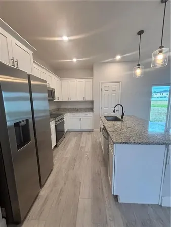 a kitchen with stainless steel appliances granite countertop a refrigerator a sink and a stove