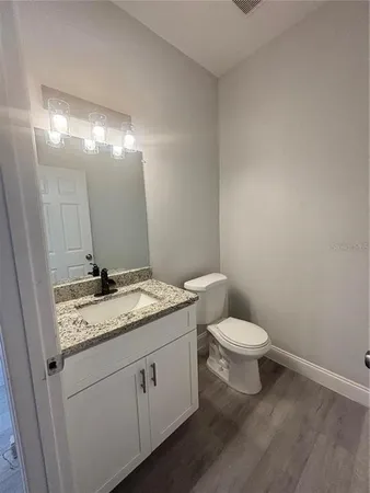 a bathroom with a granite countertop sink a toilet and a mirror