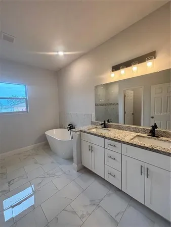 a bathroom with a granite countertop sink mirror and bathtub