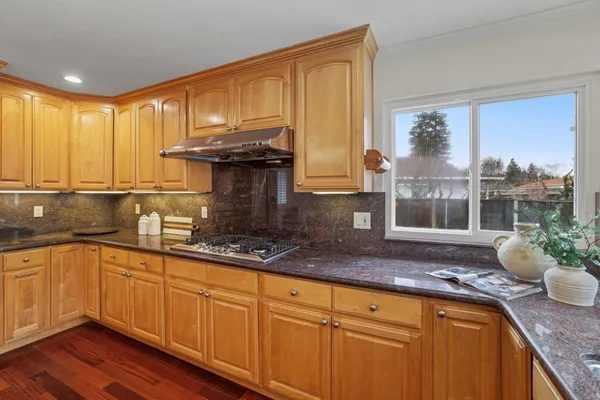 a kitchen with stainless steel appliances granite countertop a sink a stove and wooden cabinets