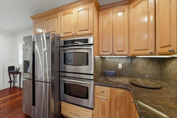 a kitchen with stainless steel appliances granite countertop a refrigerator a stove and a sink with wooden floor