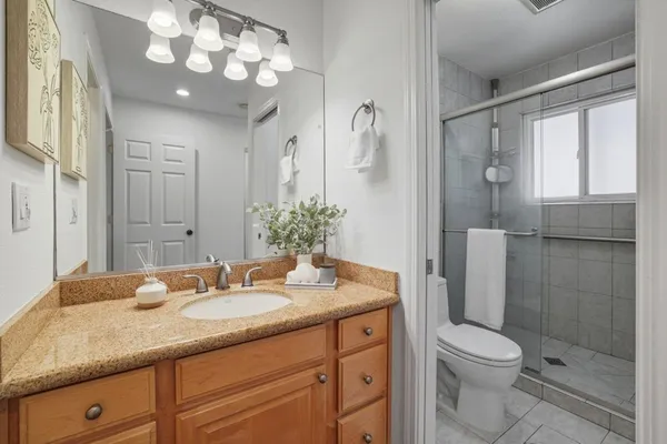 a bathroom with a granite countertop sink a toilet and shower
