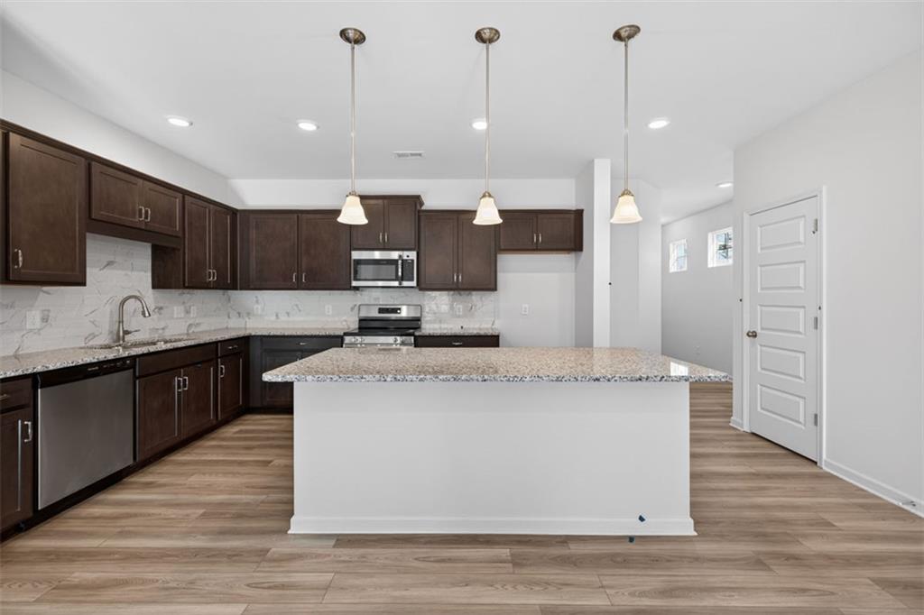 224 Bastian Drive, Unit 116 Villa Rica, GA 30180 - Photo 4 of 33 a large kitchen with stainless steel appliances kitchen island granite countertop a stove a sink a refrigerator and a microwave