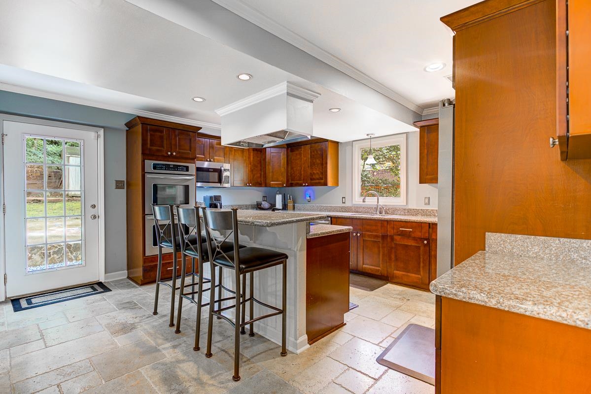 5699 Normandy Road Memphis, TN 38120 - Photo 6 of 34 Kitchen featuring stone tile flooring, warm wood cabinetry, Granite countertops, a breakfast bar, and stainless steel appliances!