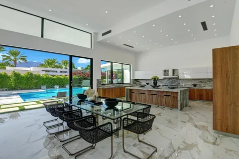 a living room with stainless steel appliances kitchen island granite countertop a table chairs and a barbeque