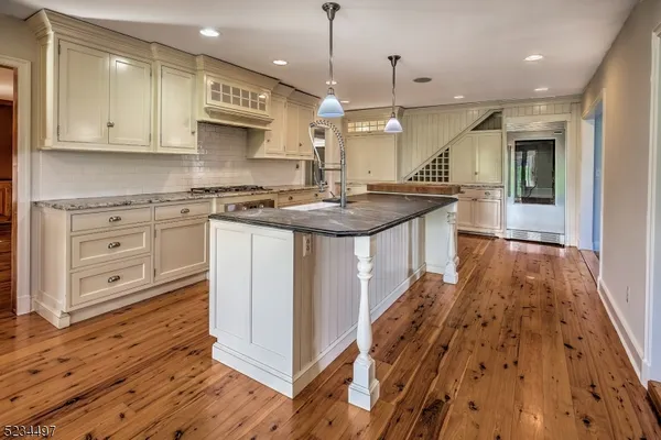 a kitchen with stainless steel appliances granite countertop a sink a stove and a wooden floors