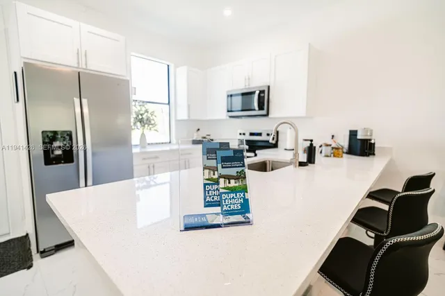 a kitchen with stainless steel appliances a microwave a sink a refrigerator a window and cabinets