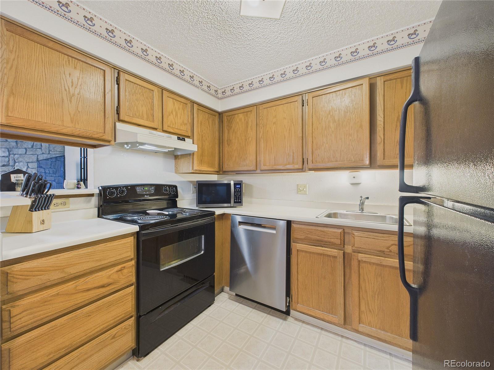 10251 West 44th Avenue, Unit 2203 Wheat Ridge, CO 80033 - Photo 7 of 20 a kitchen with stainless steel appliances granite countertop a sink stove and refrigerator