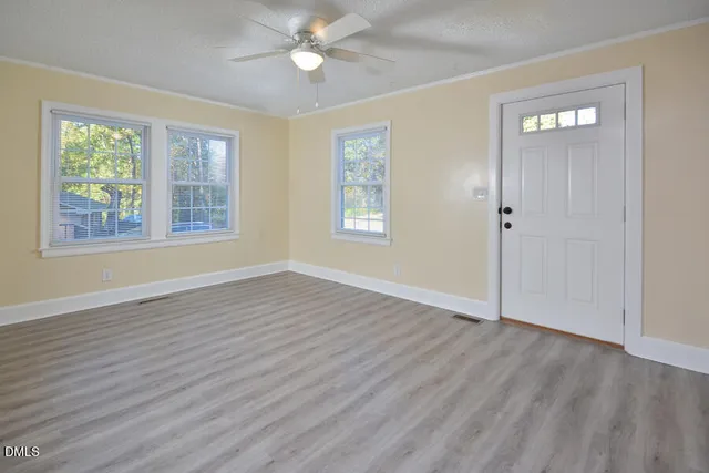 a view of an empty room with wooden floor and a window