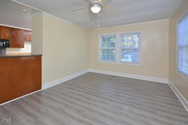 a view of an empty room with a window and wooden floor
