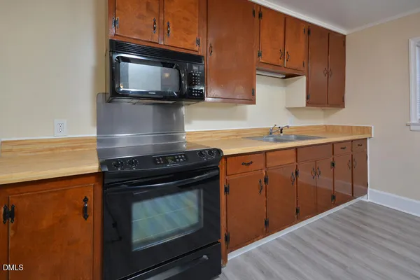 a kitchen with stainless steel appliances a stove a microwave oven cabinets and wooden floor