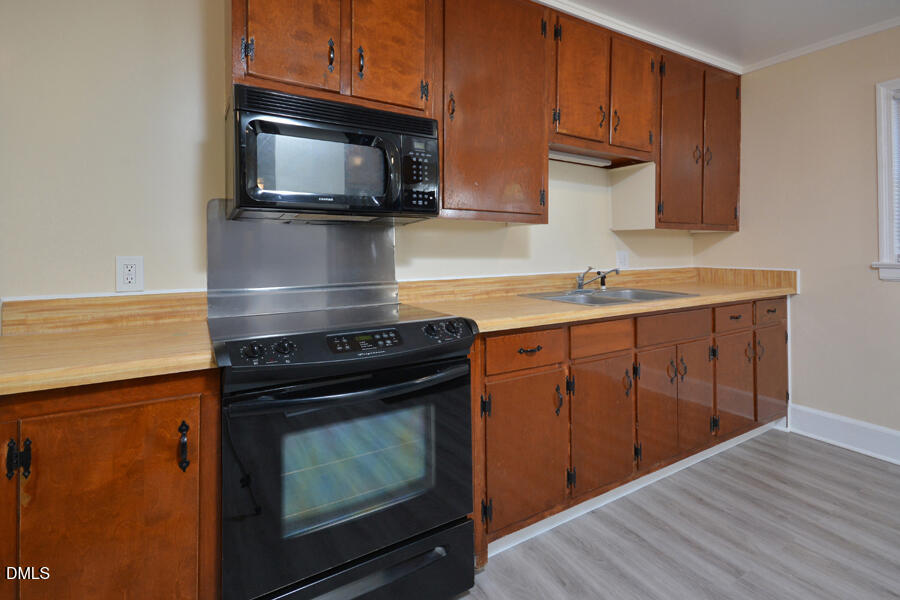 721 Peyton Avenue Durham, NC 27703 - Photo 10 of 25 a kitchen with stainless steel appliances a stove a microwave oven cabinets and wooden floor