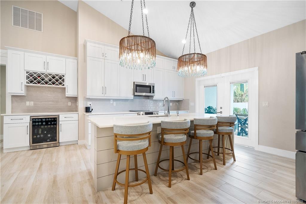 1269 Northwest Fork Road Stuart, FL 34994 - Photo 2 of 92 a kitchen with stainless steel appliances a dining table chairs a sink and dishwasher a refrigerator with wooden floor