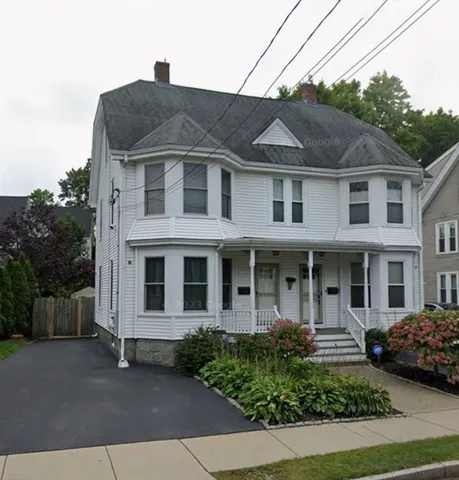 a view of a white house with large windows next to a yard