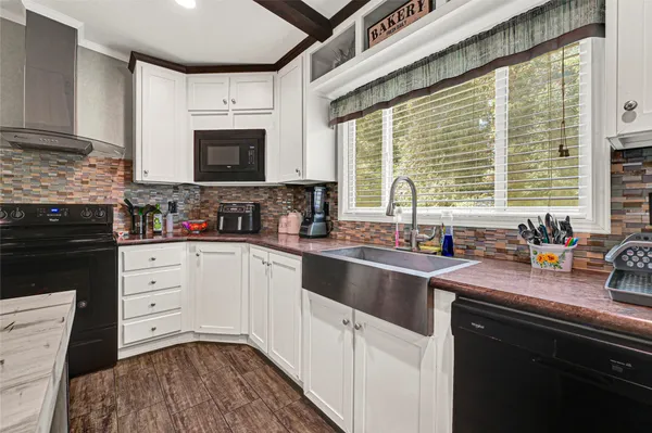 a kitchen with stainless steel appliances white cabinets a sink a stove a microwave a sink and cabinets